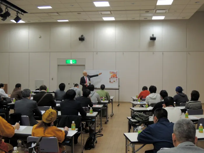 多数の受講者が着席する研修会場で、前方のホワイトボードを使って講義を行う宮内海。満席の参加者が熱心に聞き入っている。