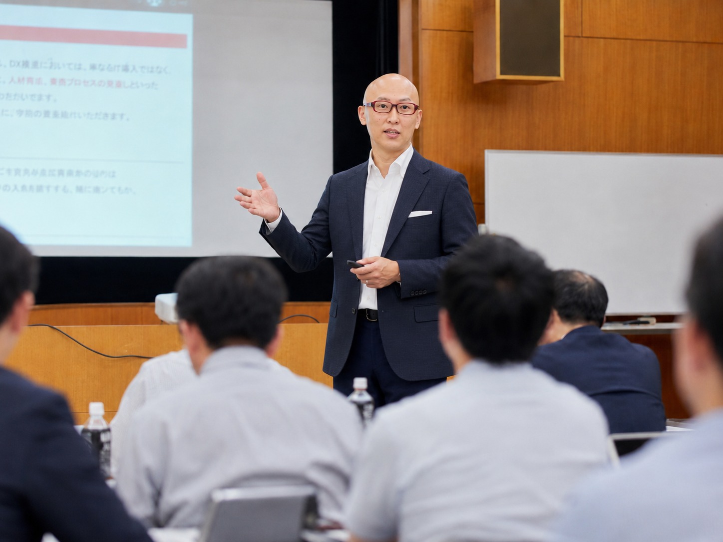 セミナー会場で、受講者を前にジャケット姿で身ぶりを交えて話す宮内海。スクリーンに資料を投影しながら登壇している様子。